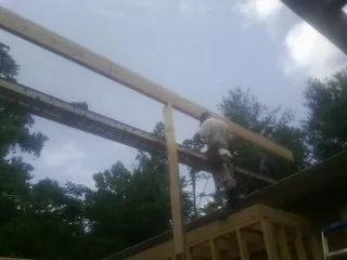 Carpenter setting a ridge beam over a new addition frame — Ice Dam Removal by Roofing Brothers in Bassett