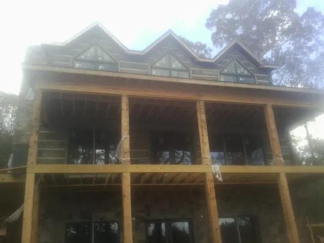 Dormers and porch framing on a large log home under construction — Roof Coating work by our crew in Bassett
