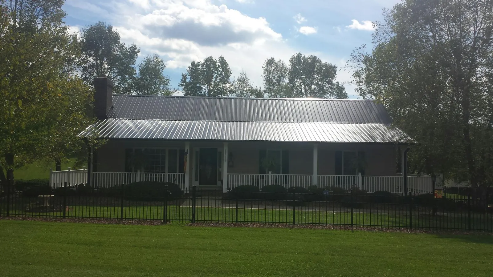 Gray metal roof on a brick ranch with a full width front porch — Gutter Guard Installation work by our crew in Bassett