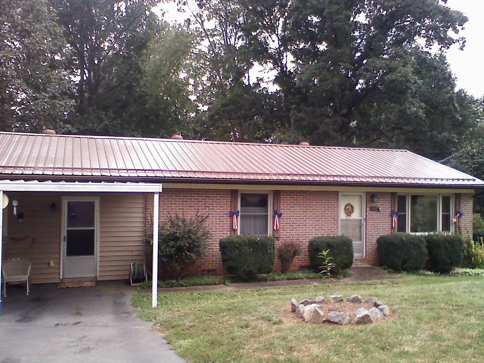 Bronze metal roof and carport on a brick ranch home — Roof Repair work by our crew in Bassett