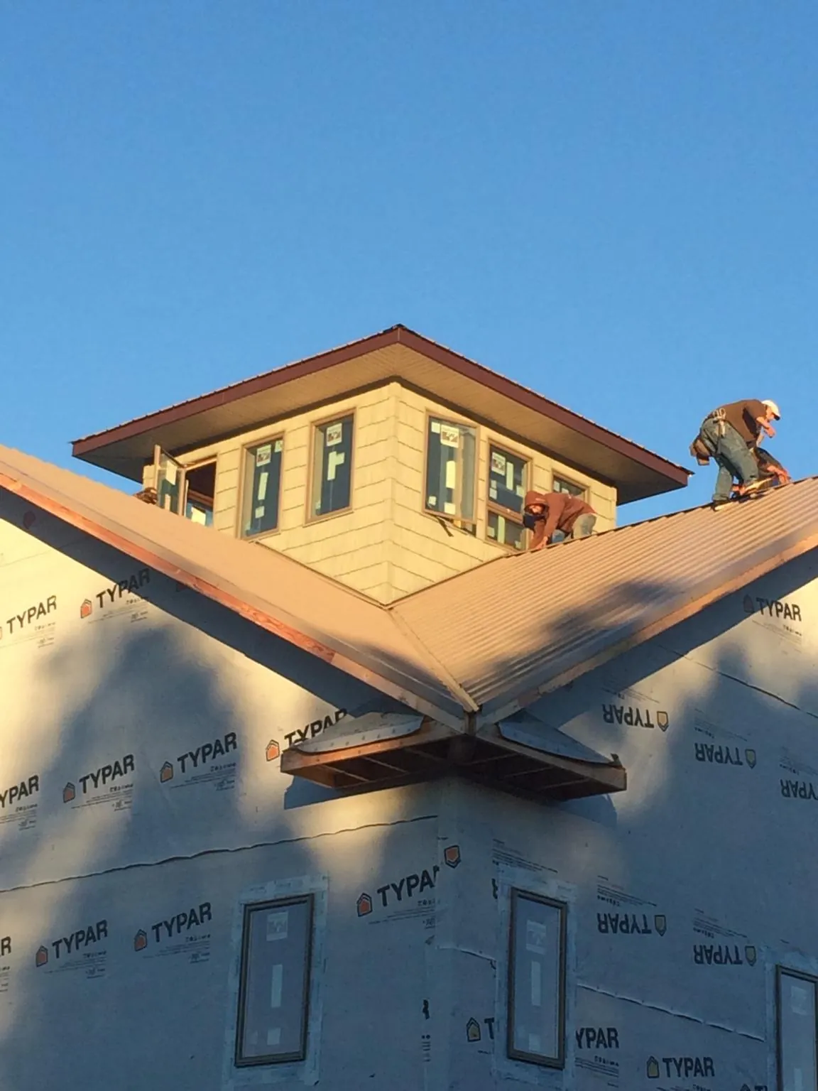 Roofers working around a rooftop cupola on a new metal roof at sunset — Roof Waterproofing in Bassett by Roofing Brothers